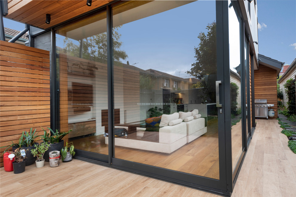 Photo of a mid-sized contemporary two-storey house exterior in Melbourne with wood siding, a flat roof and a metal roof.