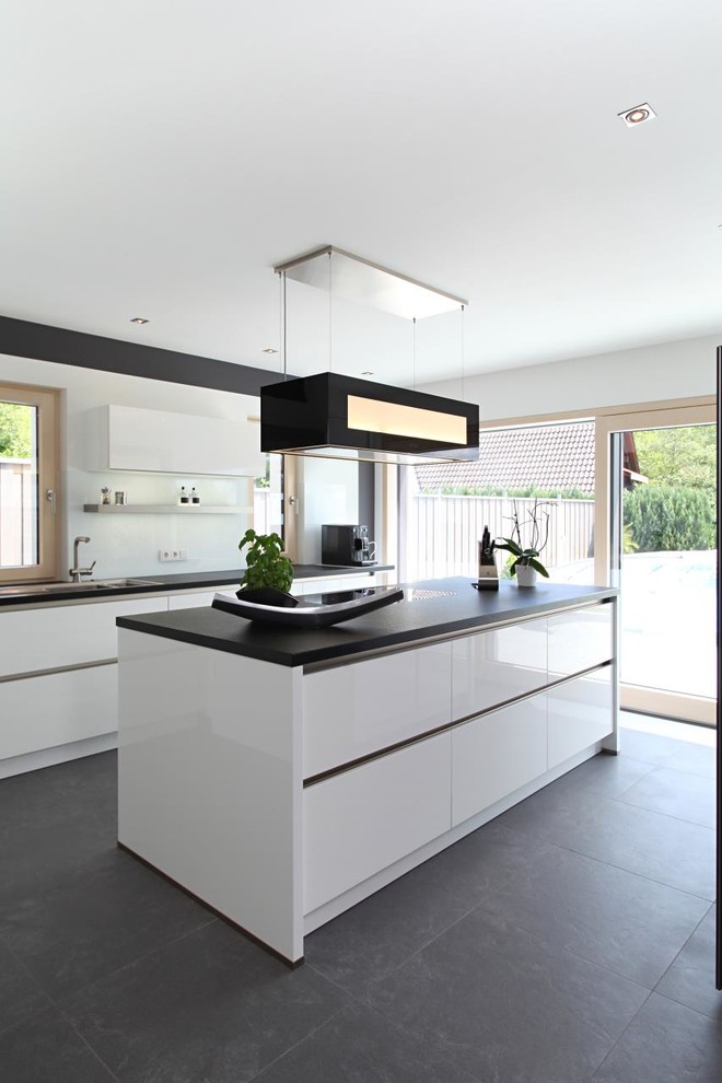 Mid-sized contemporary open plan kitchen in Other with a drop-in sink, flat-panel cabinets, white cabinets, white splashback, glass sheet splashback and with island.