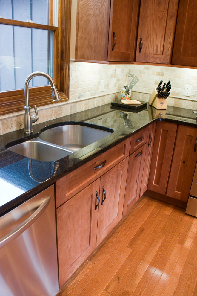 Kitchen - mid-sized l-shaped light wood floor kitchen idea with an undermount sink, shaker cabinets, medium tone wood cabinets, granite countertops, beige backsplash, stone tile backsplash, stainless steel appliances and no island