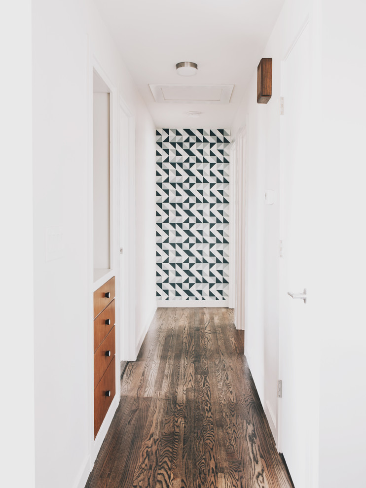This is an example of a small midcentury hallway in Seattle with white walls and dark hardwood floors.