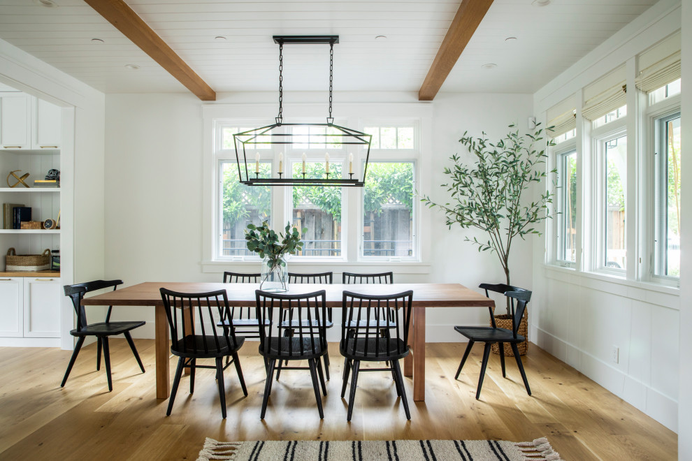 Foto di una grande sala da pranzo aperta verso la cucina country con pareti bianche, pavimento in legno massello medio e pavimento marrone