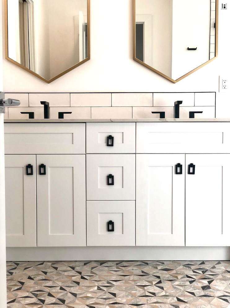 This is an example of an eclectic master bathroom in Miami with recessed-panel cabinets, white cabinets, a corner shower, a one-piece toilet, white tile, subway tile, white walls, porcelain floors, an undermount sink, tile benchtops, black floor, a sliding shower screen and beige benchtops.