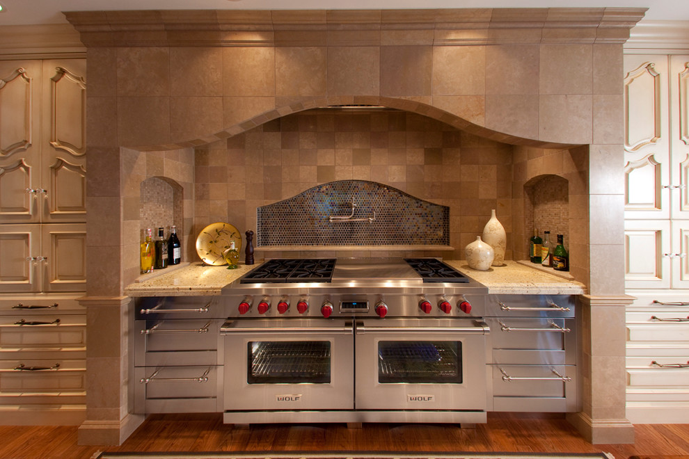 Example of a medium tone wood floor kitchen design with a farmhouse sink, raised-panel cabinets, wood countertops, mosaic tile backsplash, paneled appliances and two islands