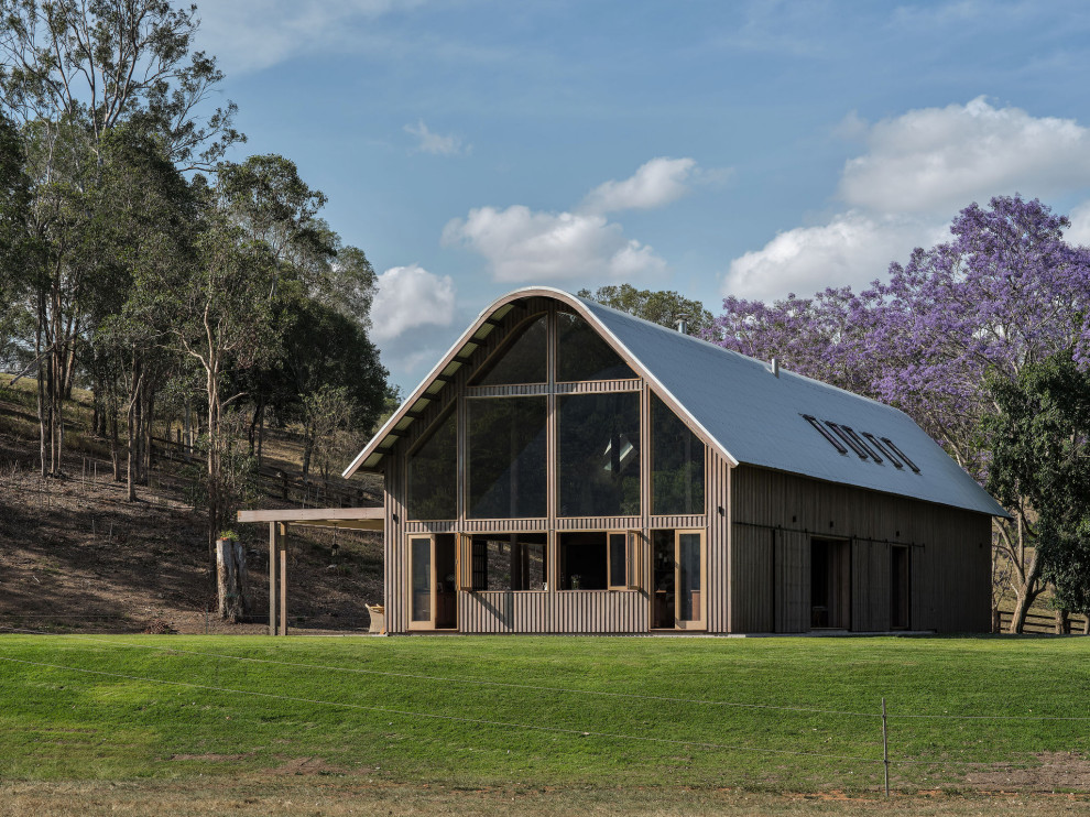 Photo of a mid-sized country two-storey house exterior in Brisbane with wood siding, a gable roof and a metal roof.