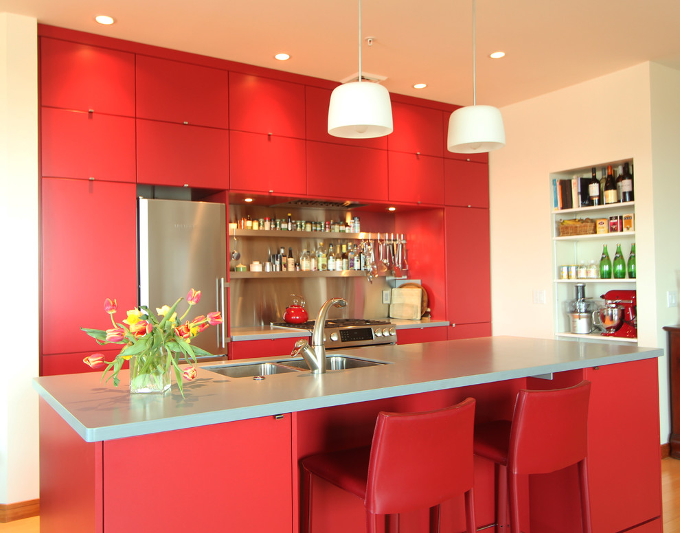 Design ideas for a small modern open plan kitchen in Other with an undermount sink, flat-panel cabinets, red cabinets, solid surface benchtops, metal splashback, stainless steel appliances, medium hardwood floors and with island.