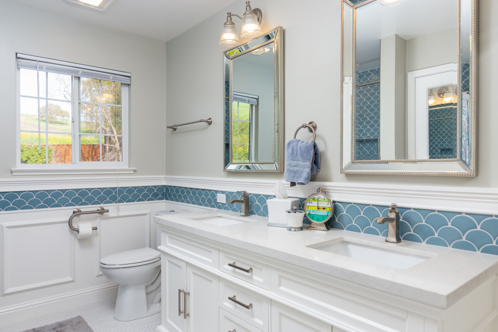 Photo of a transitional bathroom in San Francisco with recessed-panel cabinets, white cabinets, blue tile, grey walls, mosaic tile floors, an undermount sink, white floor, white benchtops, a double vanity, a built-in vanity and decorative wall panelling.