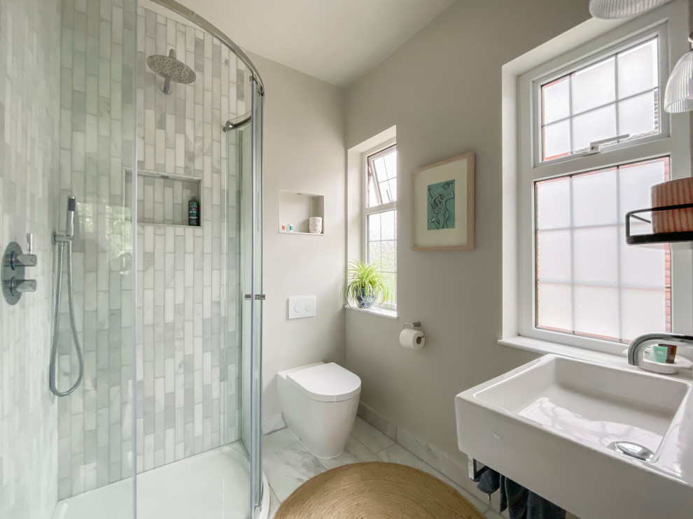 This is an example of a small scandinavian master bathroom in Other with a corner shower, a wall-mount toilet, gray tile, ceramic tile, ceramic floors, grey floor, a sliding shower screen, a single vanity, a floating vanity and vaulted.