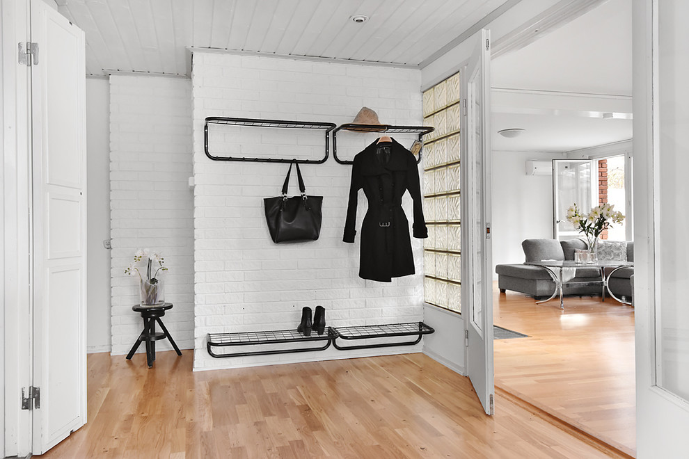 This is an example of a mid-sized scandinavian entryway in Stockholm with white walls and medium hardwood floors.