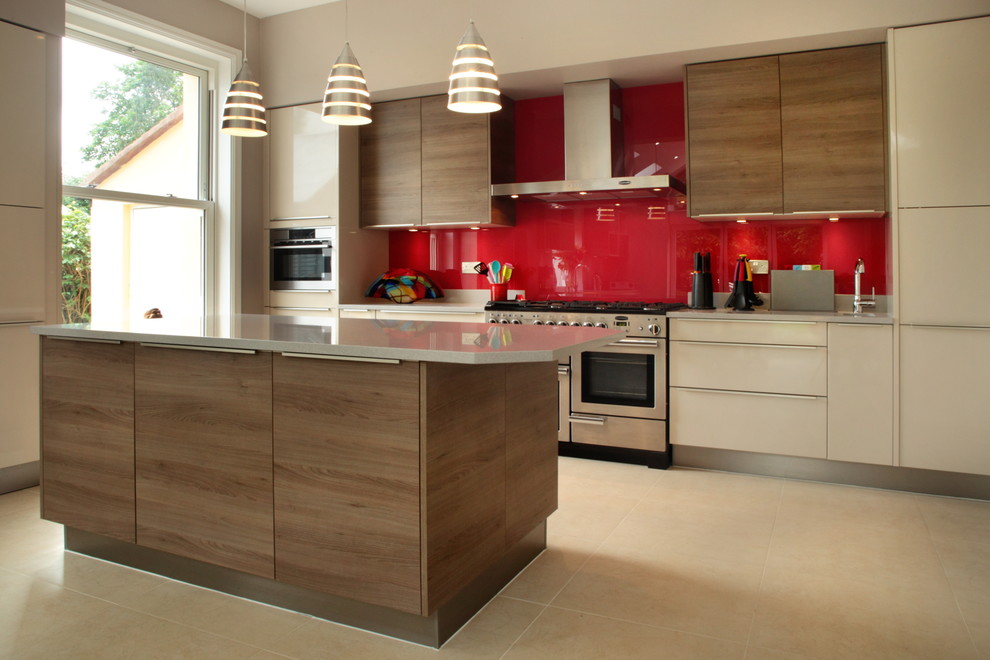 Large contemporary galley open plan kitchen in Buckinghamshire with quartzite benchtops, red splashback, stainless steel appliances, with island, an undermount sink, flat-panel cabinets, beige cabinets, glass sheet splashback and porcelain floors.