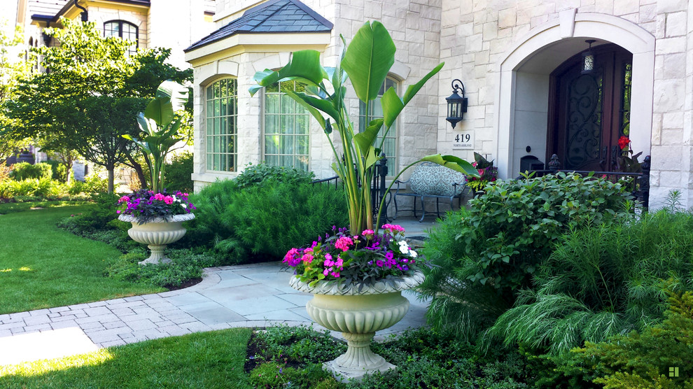 Mid-sized traditional front yard verandah in Chicago with a container garden and natural stone pavers.