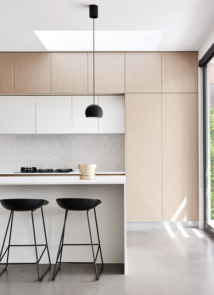 Photo of a contemporary galley kitchen in Melbourne with with island, ceramic splashback, flat-panel cabinets, light wood cabinets, white splashback, panelled appliances, concrete floors and grey floor.