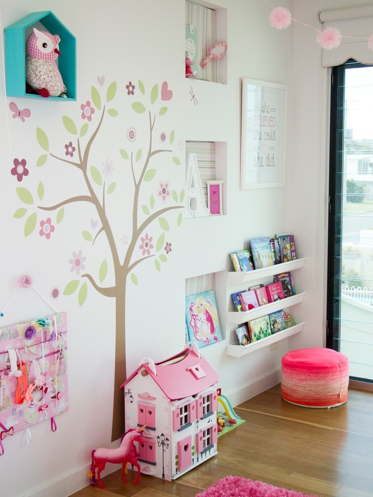 Photo of a mid-sized contemporary toddler room for girls in Gold Coast - Tweed with beige walls and light hardwood floors.
