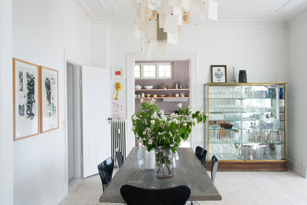 This is an example of a large scandinavian separate dining room in Copenhagen with white walls, light hardwood floors and no fireplace.