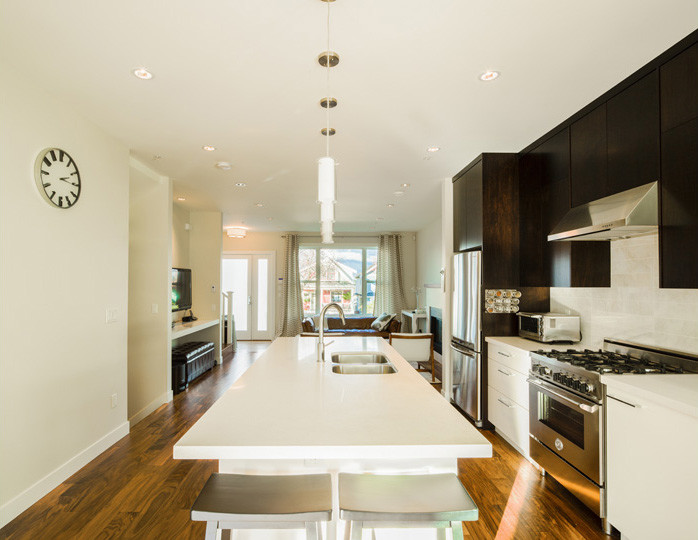 Inspiration for a mid-sized transitional galley medium tone wood floor kitchen remodel in Vancouver with a drop-in sink, recessed-panel cabinets, dark wood cabinets, marble countertops, gray backsplash, ceramic backsplash and stainless steel appliances