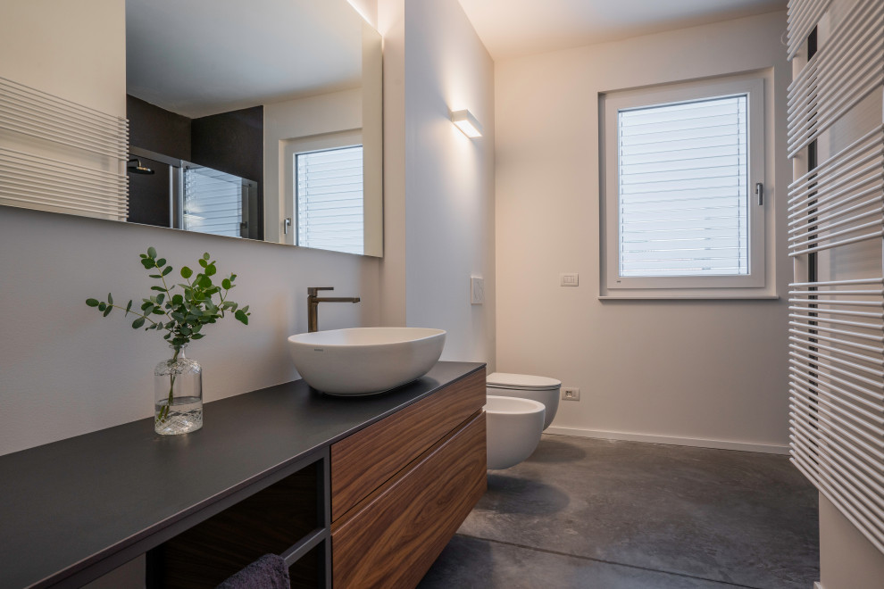 Mid-sized industrial 3/4 bathroom in Venice with grey cabinets, a curbless shower, a wall-mount toilet, white walls, concrete floors, a vessel sink, grey floor, an open shower, grey benchtops, a single vanity and a floating vanity.