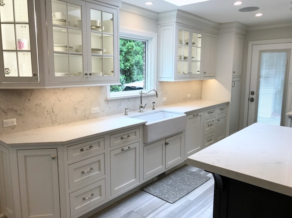 Open concept kitchen - mid-sized transitional u-shaped light wood floor and brown floor open concept kitchen idea with a farmhouse sink, recessed-panel cabinets, white cabinets, marble countertops, white backsplash, marble backsplash, stainless steel appliances and an island