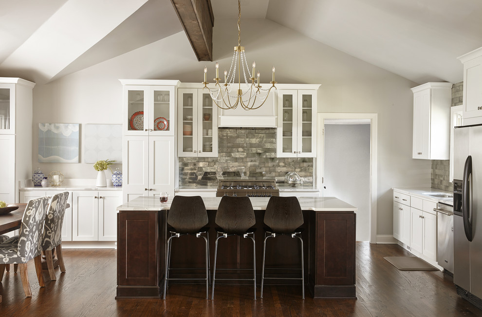 Design ideas for a large contemporary l-shaped kitchen in Nashville with an undermount sink, glass-front cabinets, white cabinets, marble benchtops, metallic splashback, mirror splashback, stainless steel appliances, medium hardwood floors, with island and brown floor.