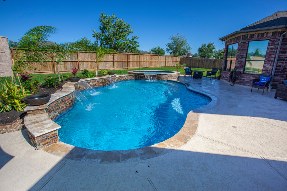 Mid-sized traditional backyard custom-shaped pool in Houston with decking.