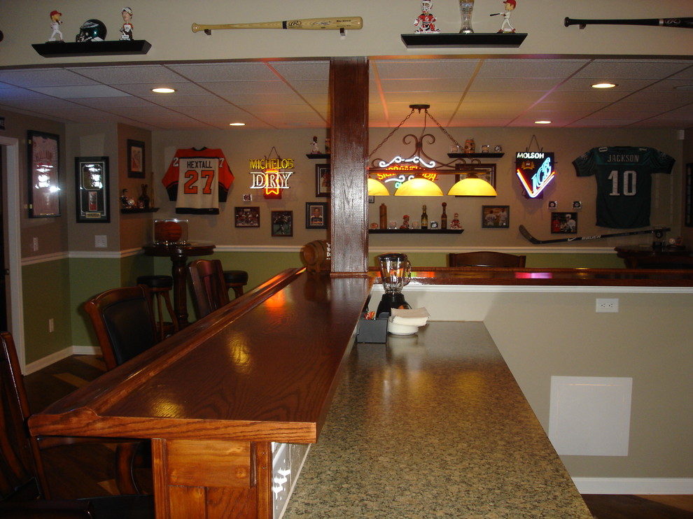 This is an example of a large traditional u-shaped seated home bar in Philadelphia with an undermount sink, recessed-panel cabinets, light wood cabinets, wood benchtops, dark hardwood floors, brown floor and brown benchtop.