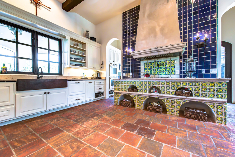 Inspiration for a mid-sized arts and crafts galley eat-in kitchen in Austin with a farmhouse sink, limestone benchtops, blue splashback, terra-cotta splashback, terra-cotta floors and no island.