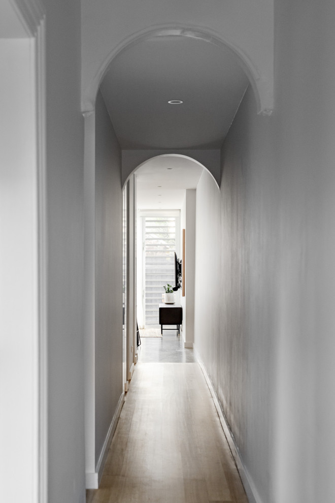Kleiner Moderner Flur mit weißer Wandfarbe, hellem Holzboden und braunem Boden in Sydney