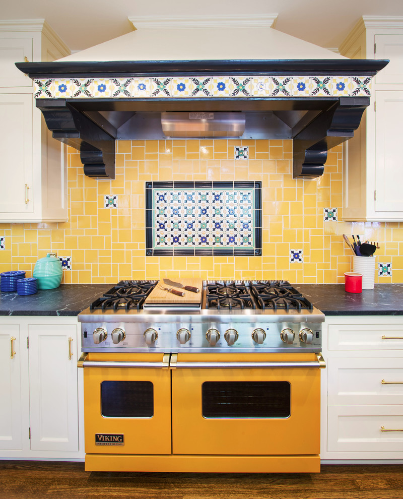 This is an example of a large mediterranean kitchen in Los Angeles with recessed-panel cabinets, white cabinets, soapstone benchtops, yellow splashback, mosaic tile splashback, stainless steel appliances, medium hardwood floors and brown floor.