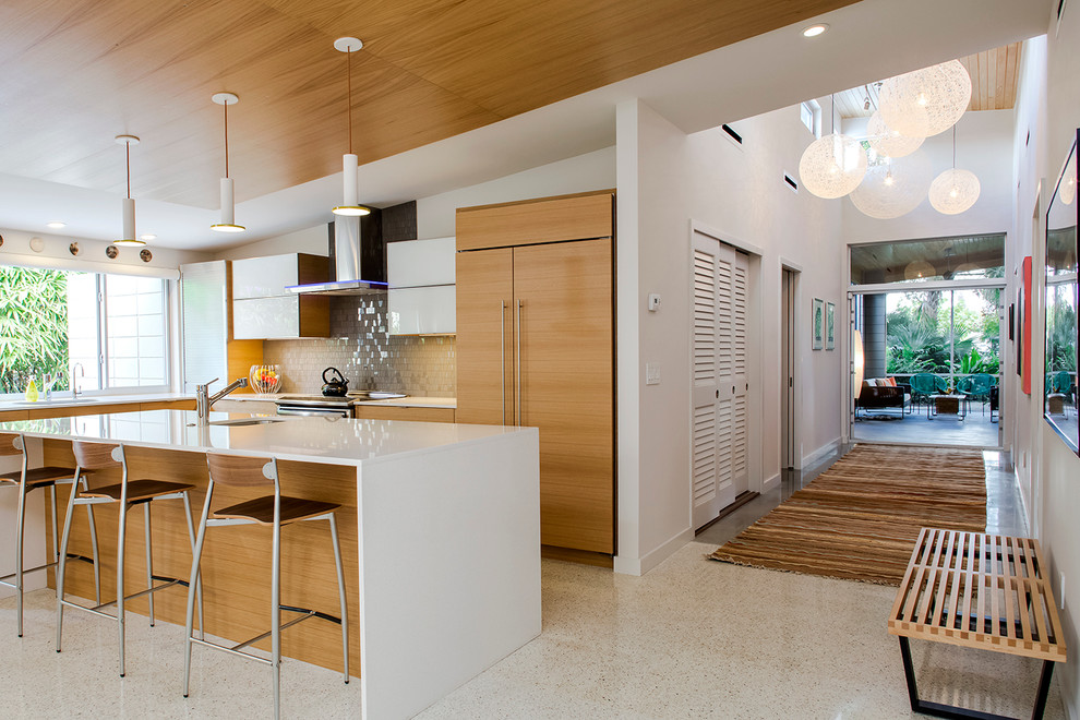 Midcentury l-shaped kitchen in Tampa with flat-panel cabinets, light wood cabinets, grey splashback, glass tile splashback, concrete floors and with island.