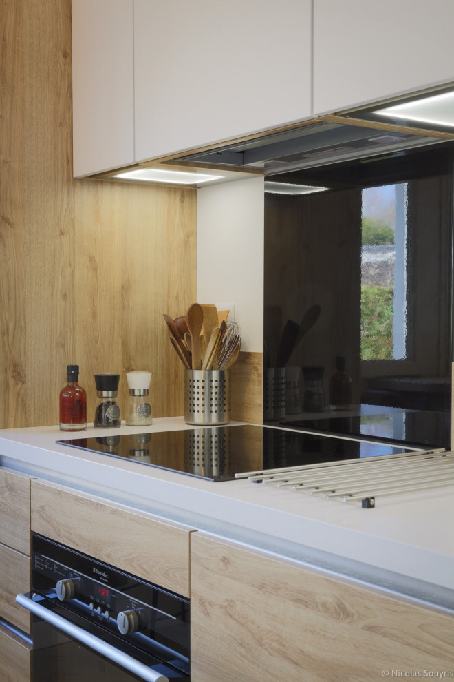 Medium sized scandi galley enclosed kitchen in Paris with an integrated sink, beaded cabinets, white cabinets, composite countertops, white splashback, wood splashback, black appliances, ceramic flooring, no island, beige floors and white worktops.