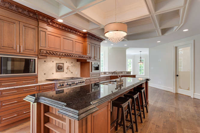 Example of a large transitional single-wall medium tone wood floor open concept kitchen design in DC Metro with a double-bowl sink, medium tone wood cabinets, beige backsplash, stainless steel appliances, raised-panel cabinets, granite countertops, metal backsplash and two islands