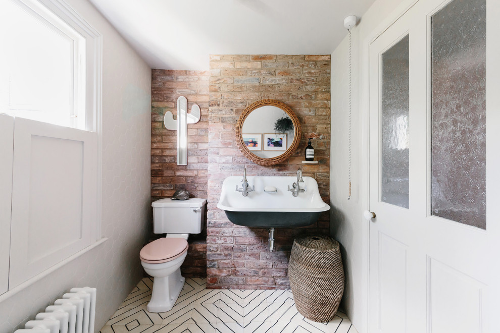 This is an example of a bohemian bathroom in London with red tiles, white walls, a trough sink, white floors, double sinks and brick walls.