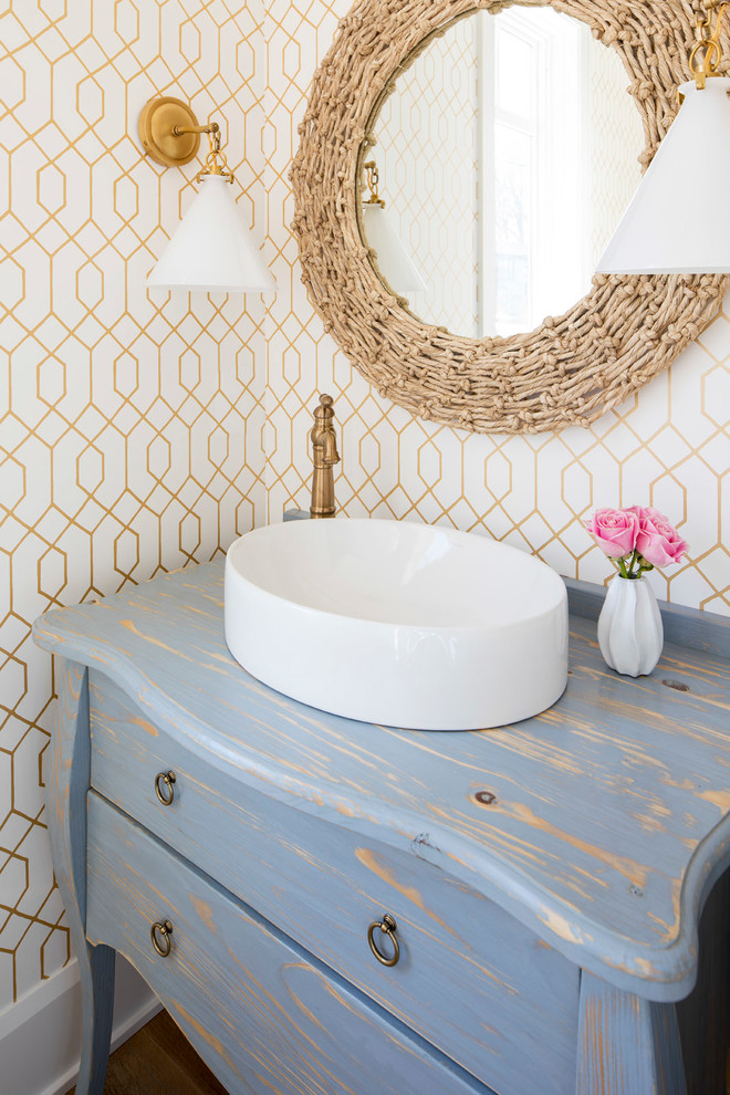 Mid-sized beach style powder room in Minneapolis with furniture-like cabinets, distressed cabinets, multi-coloured walls, a vessel sink, medium hardwood floors, wood benchtops, brown floor and blue benchtops.