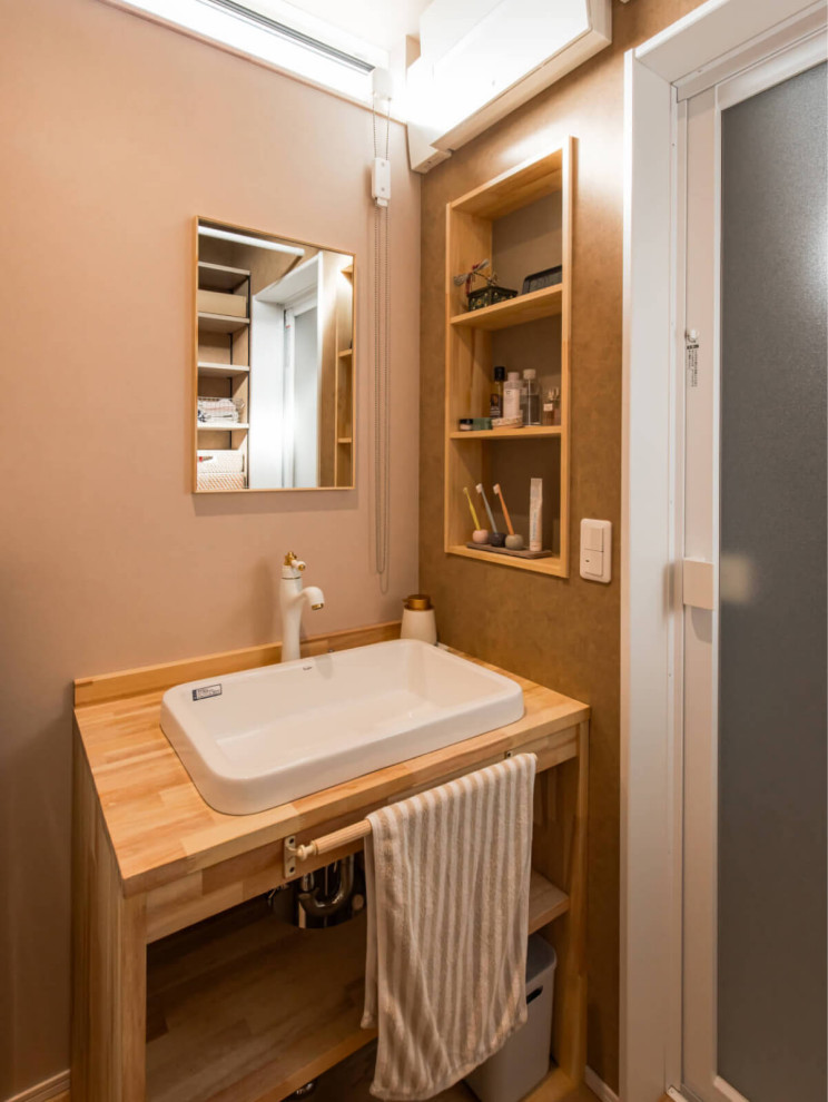 Exemple d'un WC et toilettes méditerranéen en bois clair avec un placard sans porte, un mur beige, un sol en bois brun, une vasque, un plan de toilette en bois, un sol beige, un plan de toilette beige, meuble-lavabo encastré, un plafond en papier peint et du papier peint.