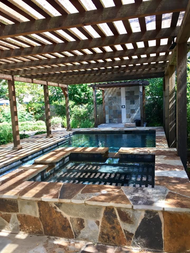 Inspiration for a mid-sized tropical backyard custom-shaped lap pool in Austin with a hot tub and natural stone pavers.