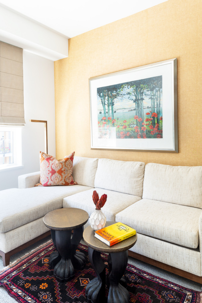 Immagine di un piccolo soggiorno eclettico con libreria, moquette, TV a parete, pavimento beige e carta da parati