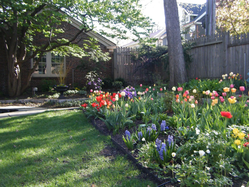 This is an example of a mid-sized traditional backyard partial sun garden for spring in Minneapolis with natural stone pavers.