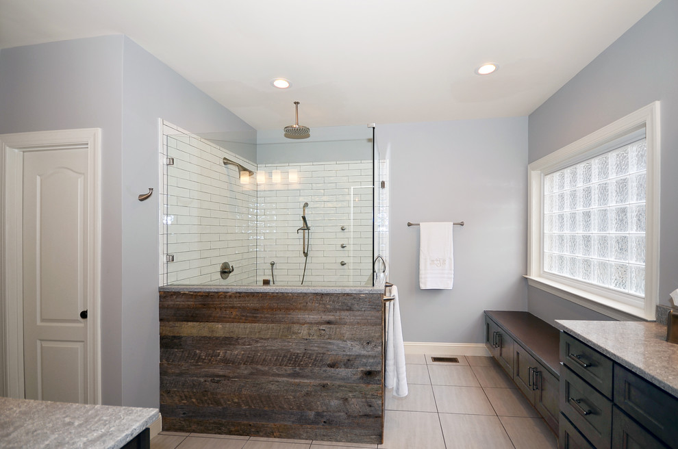 Design ideas for a mid-sized country master bathroom in Charlotte with shaker cabinets, brown cabinets, a corner shower, white tile, subway tile, blue walls, porcelain floors, an undermount sink, engineered quartz benchtops, grey floor, a hinged shower door and grey benchtops.