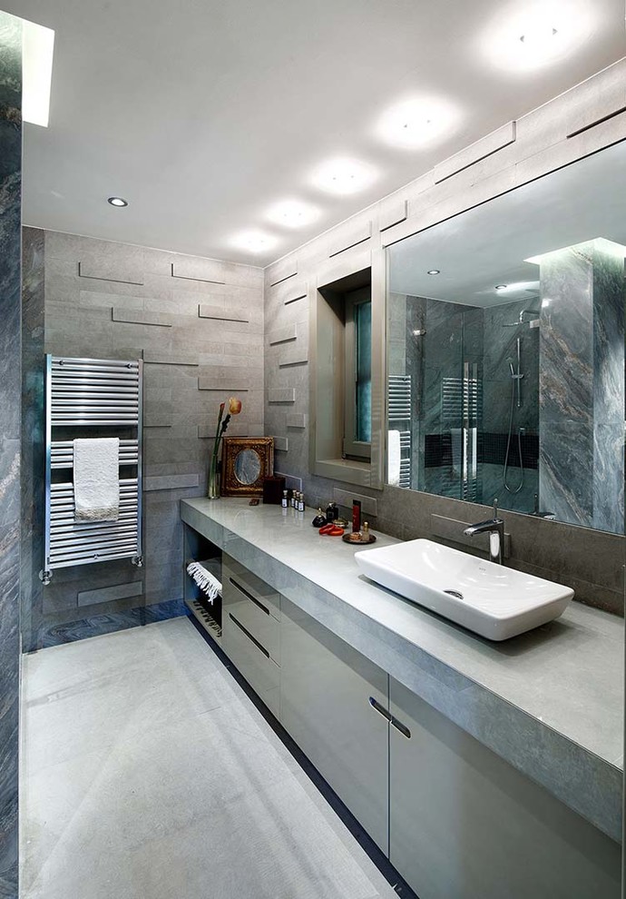 Mid-sized contemporary 3/4 bathroom in Other with a vessel sink, flat-panel cabinets, grey cabinets, marble benchtops, an alcove tub, an alcove shower, a wall-mount toilet, gray tile, stone tile, grey walls and marble floors.