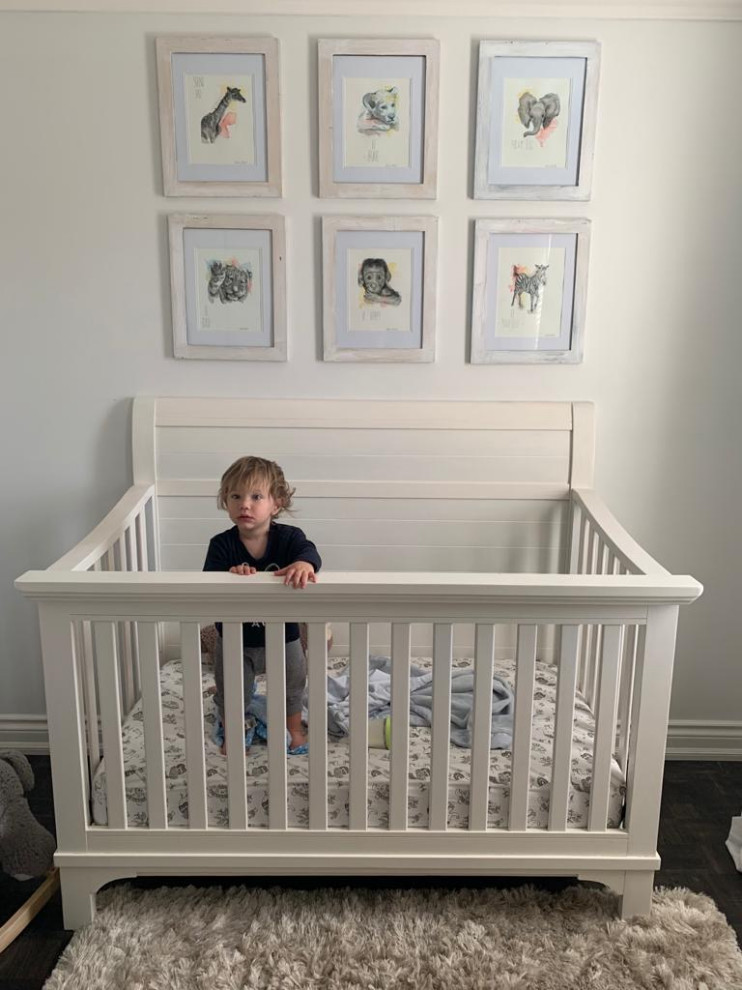 Idées déco pour une petite chambre de bébé neutre romantique avec un mur blanc et parquet foncé.