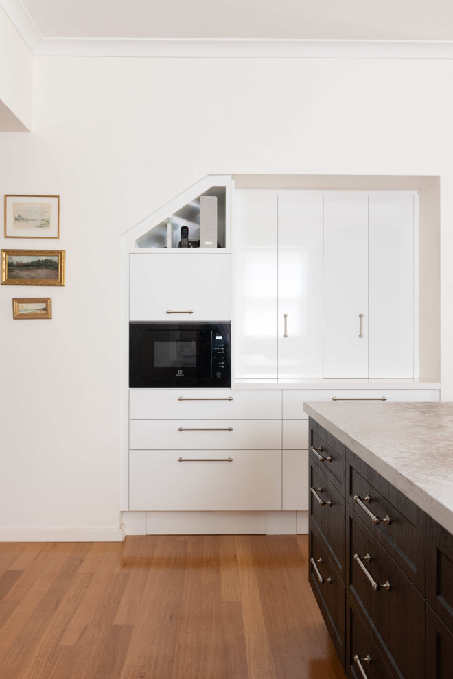 Photo of a medium sized contemporary l-shaped kitchen/diner in Perth with a double-bowl sink, white cabinets, white splashback, glass sheet splashback, stainless steel appliances, medium hardwood flooring, an island and white worktops.