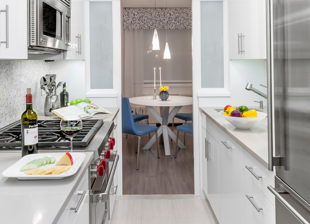 This is an example of a mid-sized modern u-shaped separate kitchen in Montreal with flat-panel cabinets, white cabinets, white splashback, glass tile splashback, stainless steel appliances, light hardwood floors, no island, solid surface benchtops and grey floor.