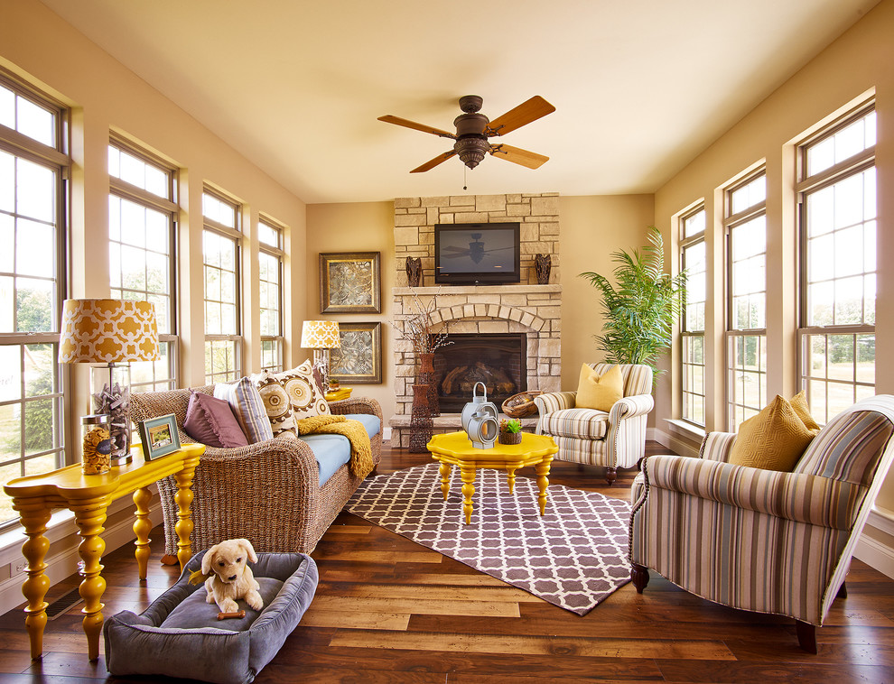 Photo of a mid-sized traditional living room in St Louis with beige walls, dark hardwood floors, a standard fireplace, a stone fireplace surround and a wall-mounted tv.