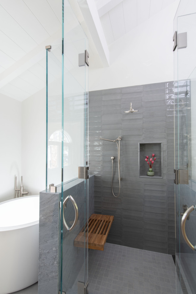 This is an example of a large coastal bathroom in Los Angeles with flat-panel cabinets, light wood cabinets, a japanese bath, an alcove shower, a one-piece toilet, grey tiles, glass tiles, grey walls, marble flooring, a vessel sink, marble worktops, grey floors, grey worktops, a shower bench, a single sink and a floating vanity unit.