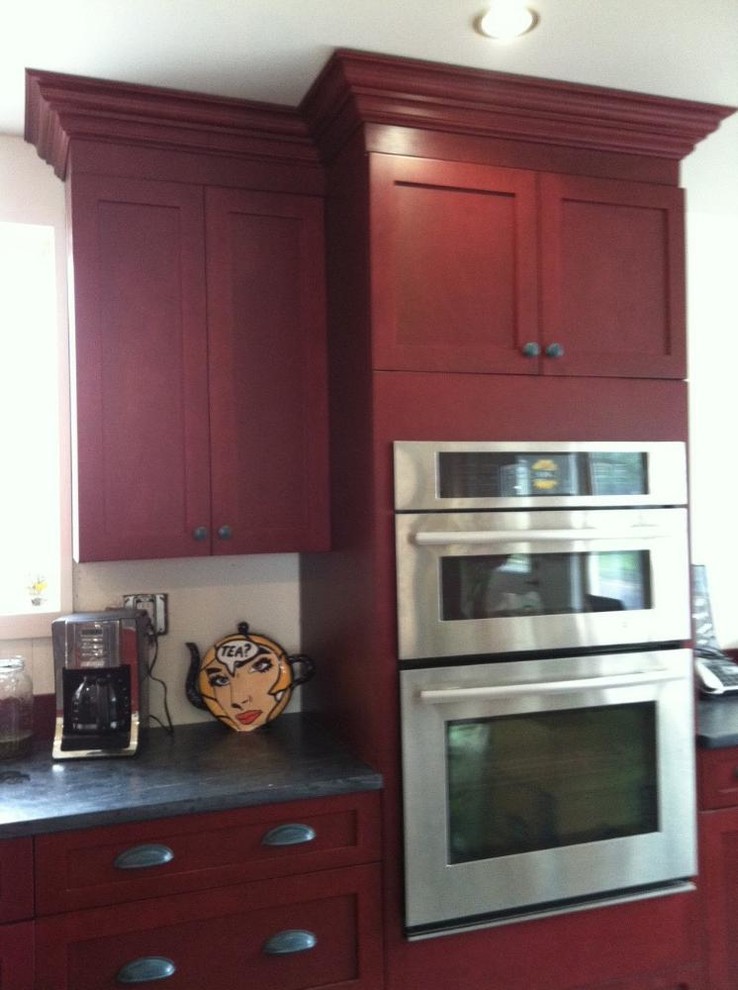 Eat-in kitchen - mid-sized transitional galley ceramic tile eat-in kitchen idea with flat-panel cabinets, red cabinets, solid surface countertops, stainless steel appliances, white walls and an island