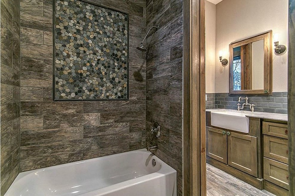 Design ideas for a mid-sized country kids bathroom in Houston with recessed-panel cabinets, dark wood cabinets, granite benchtops, a corner tub, a shower/bathtub combo, gray tile, pebble tile, beige walls and slate floors.