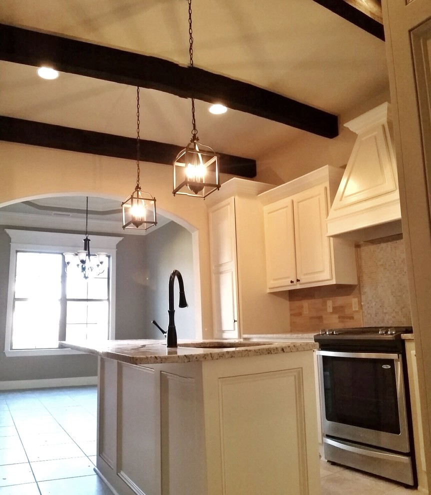 This is an example of a country l-shaped eat-in kitchen in New Orleans with raised-panel cabinets, white cabinets, granite benchtops, grey splashback, stone tile splashback, stainless steel appliances, ceramic floors, with island and an undermount sink.