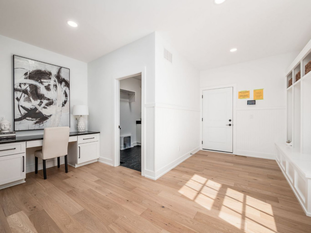 Mudroom - large transitional light wood floor and brown floor mudroom idea in Columbus with white walls and a white front door