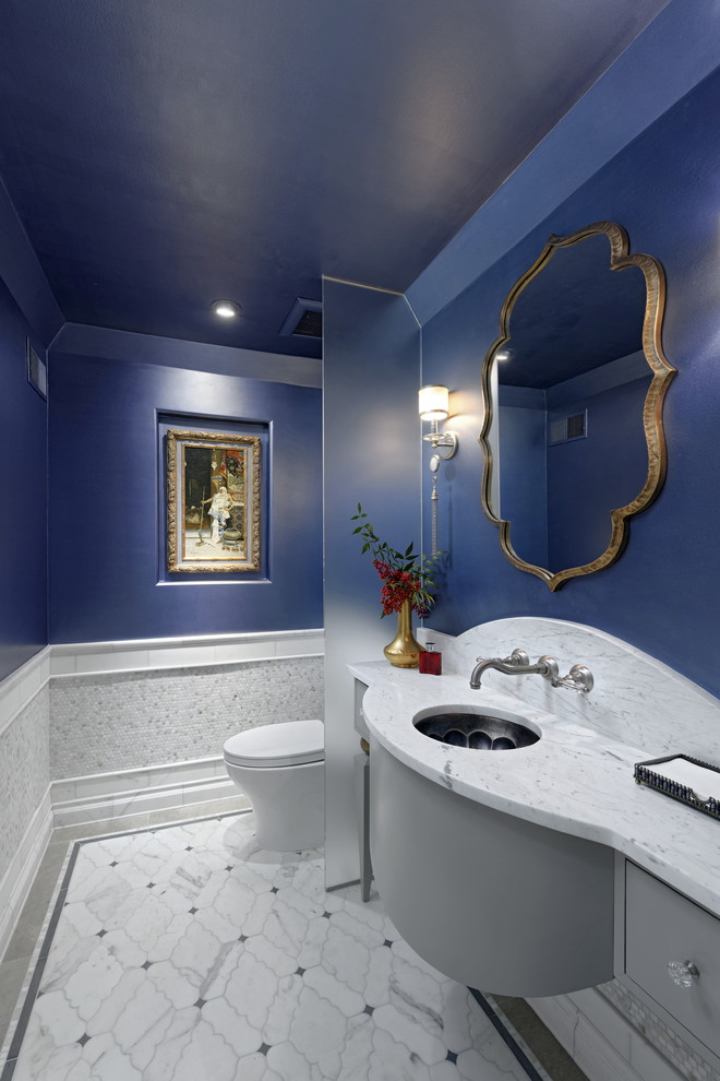 This is an example of a traditional powder room in DC Metro with furniture-like cabinets, grey cabinets, white tile, marble, blue walls, marble floors, an undermount sink, marble benchtops, white floor and white benchtops.