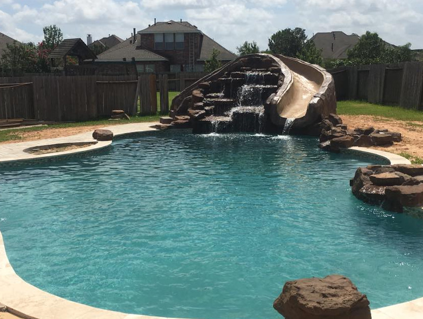 Example of a mid-sized mountain style backyard tile and custom-shaped natural water slide design in Orange County