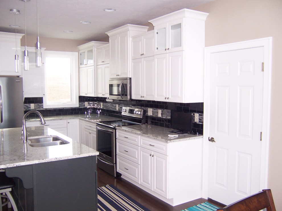 Transitional l-shaped kitchen photo with a double-bowl sink, raised-panel cabinets, white cabinets, granite countertops, stainless steel appliances and an island