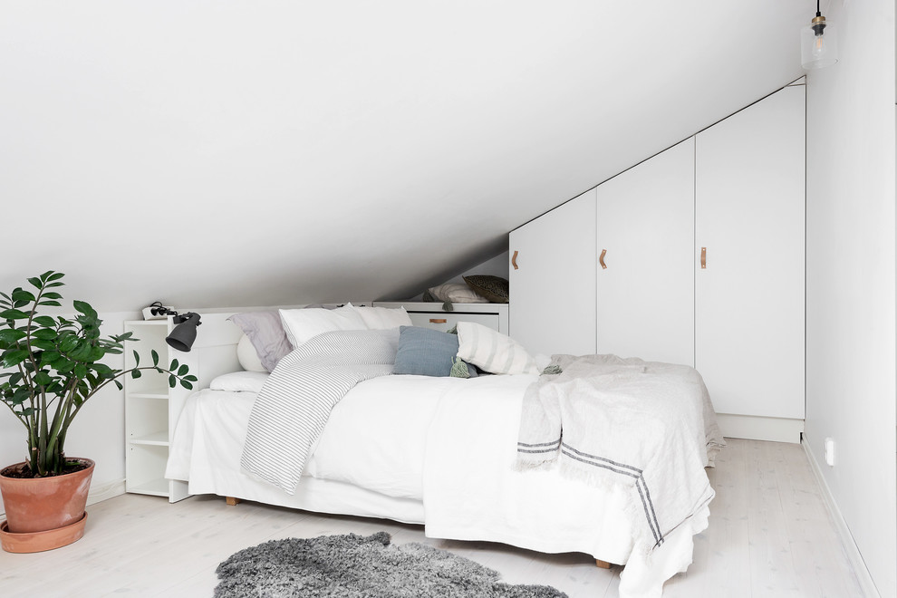 Design ideas for a small scandinavian loft-style bedroom in Gothenburg with white walls and light hardwood floors.